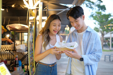 Young tourists enjoying a local dish together at a street vendor stall during their travels.