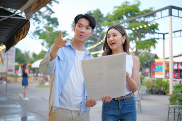 Naklejka premium Young couple deciding what to eat while looking at a menu at a vibrant outdoor street food market.