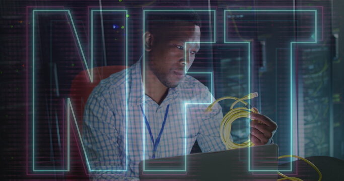 Image of nft text over african american man using laptop in server room