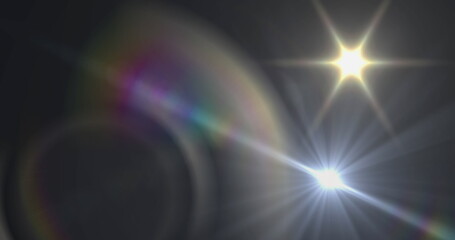 Image of white light with beam and prismatic lens flare on dark background