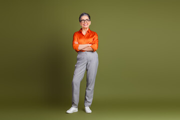 Confident senior woman in orange shirt with smart casual attire in studio taking a professional pose perfect for career themes