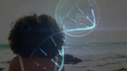 woman standing on rocky shoreline, exploring biotech using holographic DNA helix and data interface - Powered by Adobe
