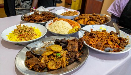 A table full of traditional Nigerian food with many different dishes, including rice, beans, and meat