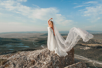 a woman in a white dress, a bride on a mountain with a blue sky. Beautiful nature, freedom, enjoyment of life. High quality photo