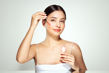 Fototapeta na wymiar Young beautiful woman applying face serum with pipette. Cosmetic procedures for facial skin care