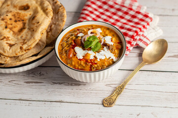 Dal Makhani is a rich, creamy lentil dish made with black lentils, kidney beans, and spices, served with soft, charred tandoori roti for a perfect meal.
