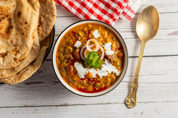 Dal Makhani is a rich, creamy lentil dish made with black lentils, kidney beans, and spices, served with soft, charred tandoori roti for a perfect meal.
