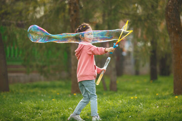 Happy Girl Blows Large Bubble in Park on Sunny Day