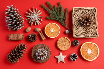 Fototapeta premium Festive winter arrangement with pine cones cinnamon stars dried oranges and nuts on red background