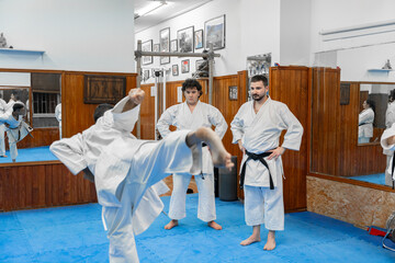 Karate practitioners training yoko geri kekomi in dojo