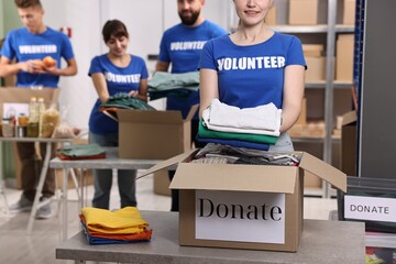 Group of volunteers packing donation goods at tables indoors, selective focus