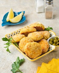 Fish cutlets from white sea fish in golden breading in a ceramic plate on a light concrete background. Recipes fish, seafood.