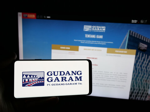 Stuttgart, Germany - 05-02-2025: Person holding smartphone with logo of Indonesian tobacco company Gudang Garam on screen in front of website. Focus on phone display.