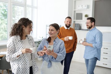 Colleagues chatting during coffee break in office