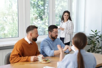 Colleagues eating and discussing work during lunch break in office