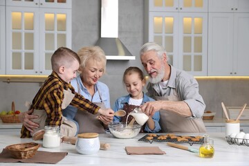 Grandparents and their grandkids cooking together at white marble table in kitchen