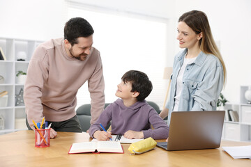 Fototapeta premium Parents helping their son with homework at wooden table indoors
