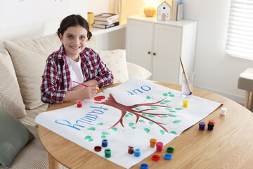Girl drawing her family tree with paints at wooden table indoors