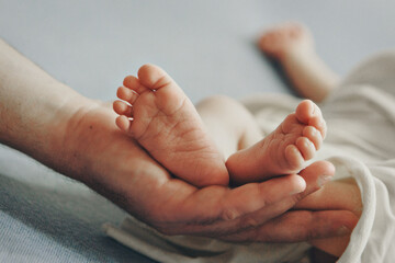Mom's arms hug the baby. the legs of a newborn. the heels, the fingers of a baby, a child. Childbirth, maternity capital, artificial insemination, IVF, mortgage, family, love. High quality photo