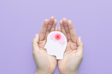 Hands holding human head with brain as pain red circle on purple background. Concept of headache,...