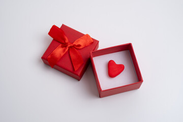 Red gift box with heart on white close-up on light background.Minimal Valentine's Day or love...