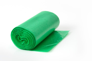 Green plastic garbage bag roll partially unrolled on white background, household waste bag for cleaning or trash disposal.