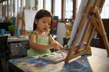 Child practicing brush techniques and color blending in creative art session.