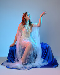 Fantasy studio portrait of a red-haired mermaid faery model wearing a white pearl gown, fairytale...