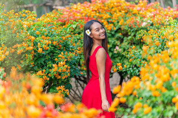 Naklejka premium Beauty shot of Asian woman in red dress immerse happily in a garden of blooming flowers