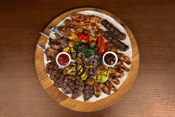 Cold cuts with beef, lamb, chicken with eggplant, red onion, barbecue sauce and adjika on the table in the restaurant on a wooden stand
