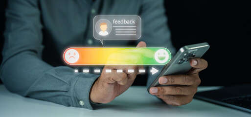 A person uses a smartphone to provide feedback on a digital satisfaction scale, ranging from unhappy to happy.