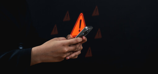A person holding a smartphone receives a warning alert, with red exclamation symbols in the...
