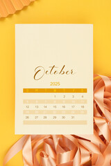 October 2025 calendar page with ribbon on yellow background.