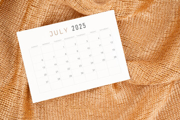 July 2025 calendar card on golden color textile.