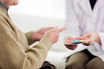 An elderly patient regains his speech skills after a stroke using flashcards with words and numbers during a psychologist's appointment at a rehabilitation clinic