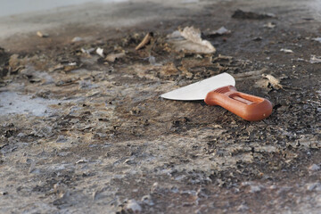Metal tool to scrape away layers of old weathered waterproof paint from roof surface.