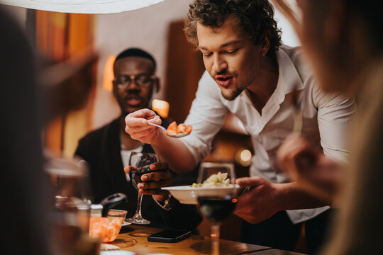 A warm and inviting scene of friends sharing food and drinks around a dining table.