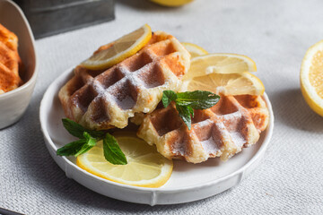 Belgian waffles made from cottage cheese with mint and lemon in a white plate on the table. Healthy breakfast