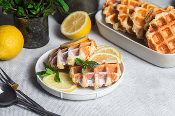 Belgian waffles made from cottage cheese with mint and lemon in a white plate on the table. Healthy breakfast