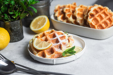 Belgian waffles made from cottage cheese with mint and lemon in a white plate on the table. Healthy breakfast
