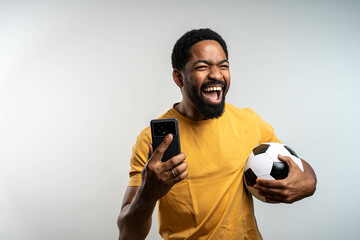 Handsome happy excited African man celebrating in euphoria mood after winning a bet, holding a...