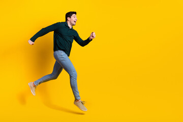 Joyful young man in casual outfit poses energetically against a vibrant yellow background, expressing fun and a stylish attitude