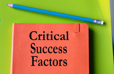 CRITICAL SUCCESS FACTORS - words on an orange notepad on a background of multi-colored folders