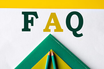 FAQ - word close-up on white sheet with folders and pencils