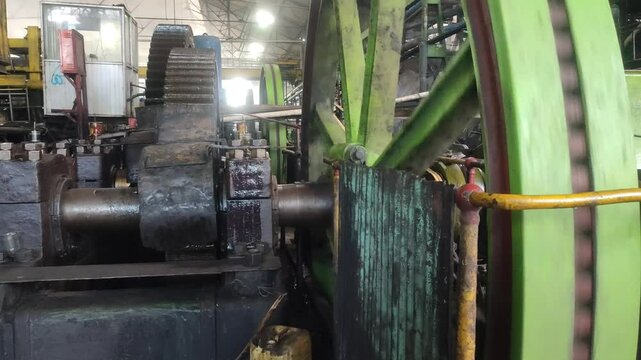 The flywheel and transmission gears of a steam engine at a sugar mill rotate in sync, delivering mechanical power to drive heavy machinery in continuous operation.