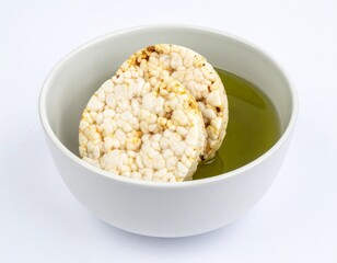 Rice cakes submerged in a clear liquid, presented in a simple white bowl