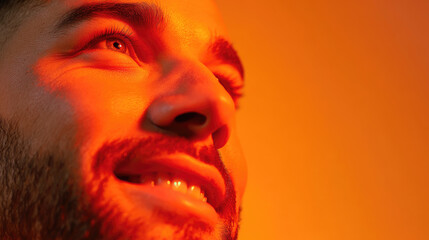 Close-up of a man's face, illuminated by warm orange light, looking hopeful