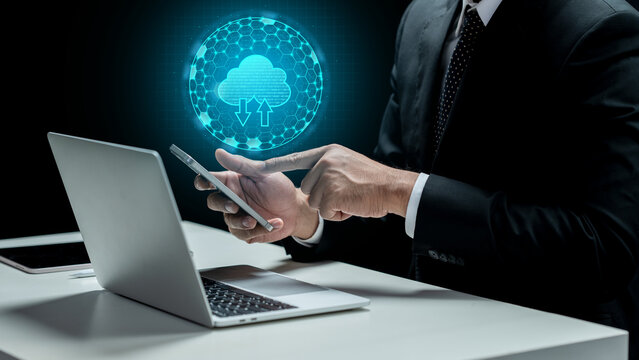 Businessman touching cellphone with cloud computing icon. Laptop and tablet on the desk. Technology innovation on the virtual screen. Concept of a Data Center