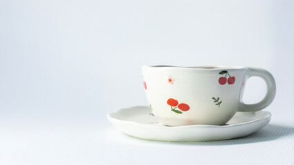 White tea cup with cherry detail isolated on white. Simple product shot for branding, packaging or minimalist editorial