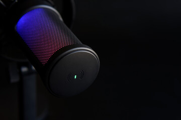 Close-up of a black RGB condenser microphone glowing with blue and red light, perfect for illustrating podcasting or streaming equipment. Photo